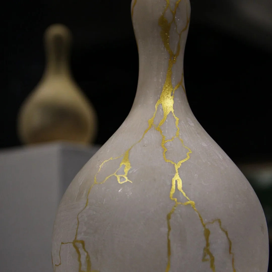Keramická váza opravená technikou kintsugi se zlatými švy podél praskliny